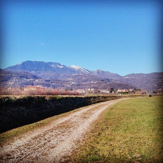 mountain, clear sky, copy space, landscape, mountain range, tranquil scene, tranquility, blue, scenics, beauty in nature, nature, road, non-urban scene, grass, field, remote, countryside, hill, country road, outdoors