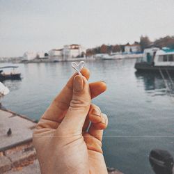 Woman holding heart shape against river