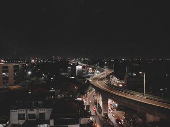 High angle view of illuminated street amidst buildings in city at night