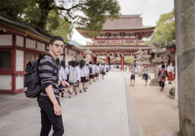 Full length portrait of young man standing against building