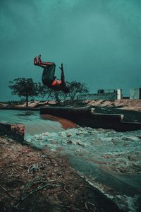 Man jumping on sea against sky