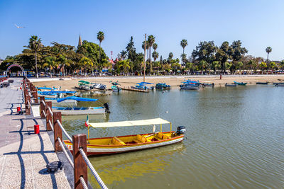 Boats moored on sea against clear blue sky