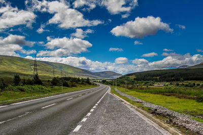 Empty road along landscape and mountains against sky