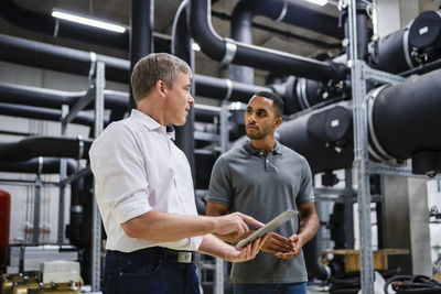 Employee and businessman with digital tablet talking in factory