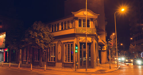 Illuminated street light by building at night