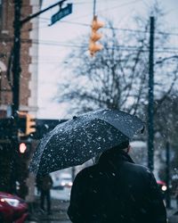 Person walking on wet road in city during winter