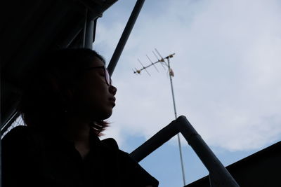 Low angle portrait of woman looking at camera against sky
