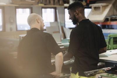 Rear view of teacher and student discussing in workshop