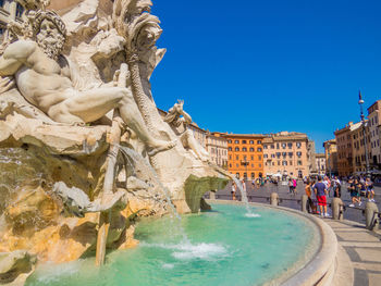 View of fountain in city against clear blue sky