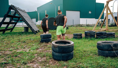 Two participants in an obstacle course dragging wheels seen from behind