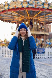 Woman in jacket, scarf, white gloves in winter, square in moscow on christmas carousel on background