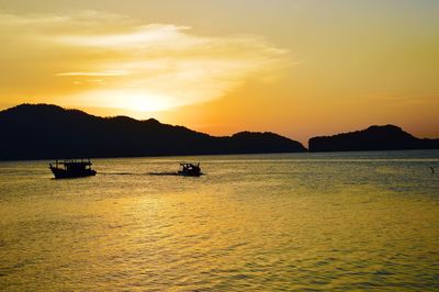 Silhouette boats sailing in sea against sky during sunset