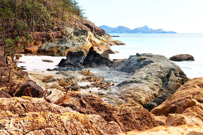 Rock formation on beach against sky