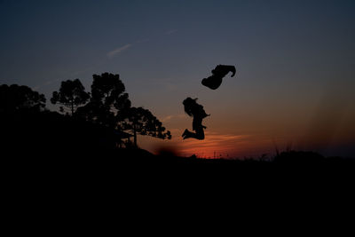 Silhouette man jumping against sky during sunset