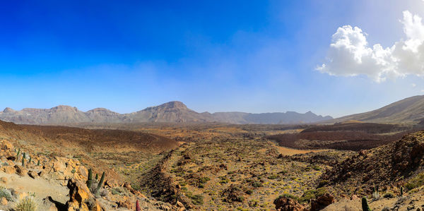 Panoramic view of landscape and mountains against blue sky