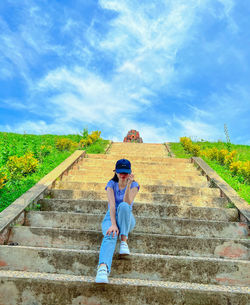 Rear view of woman walking on footpath against sky