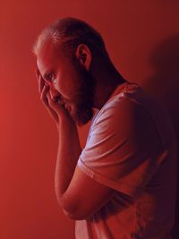 Side view of man against wall in red room