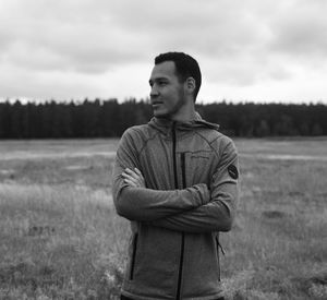 Young man looking away while standing on field