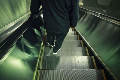 Low section of man walking on escalator