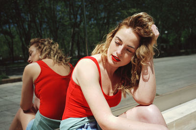 Beautiful young woman sitting against mirror