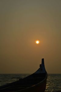 Cropped image of boat moored in sea against sky during sunset