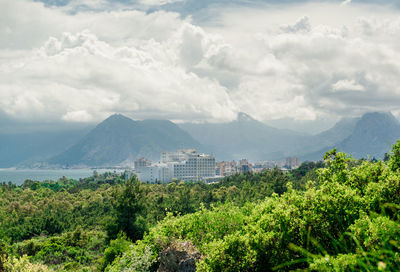 Idyllic shot of mountain range with trees in foreground against cloudy sky