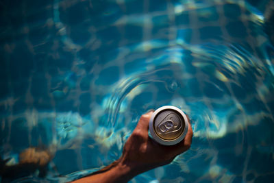 Selective focus white beer can in hand. man is soaking in the pool with an open 