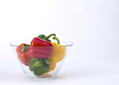 Close-up of bell peppers in glass bowl over white background