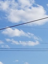 Low angle view of power cables against sky