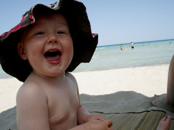 Happy boy on beach against sky