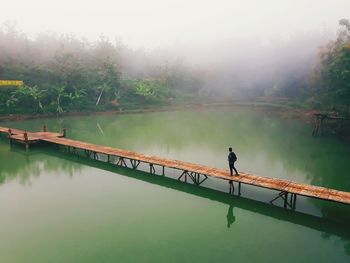 Person walking on footbridge over lake