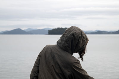 Woman on rock by lake against sky