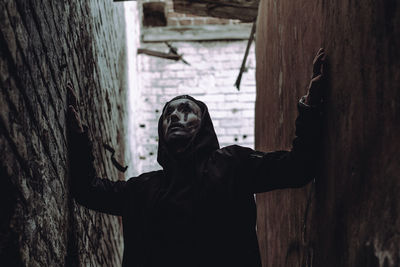 Man with face paint standing in alley