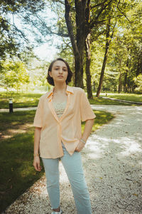 Portrait of smiling young woman standing against trees