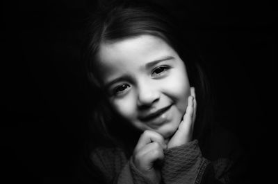 Portrait of cute girl smiling against black background