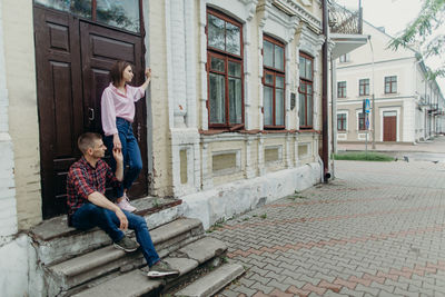 Full length of friends sitting on staircase against building