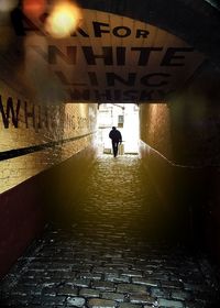 Silhouette man standing by illuminated text on wall
