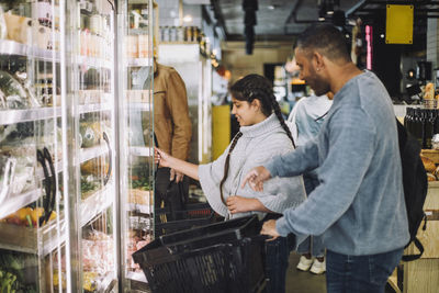 Smiling father and daughter buying grocery at convenience store