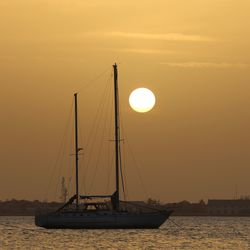 Silhouette boat sailing in sea against sky during sunset