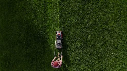 Top view of the lawn-mover worker cutting green grass garden