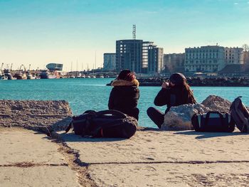 Rear view of woman looking at sea against cityscape