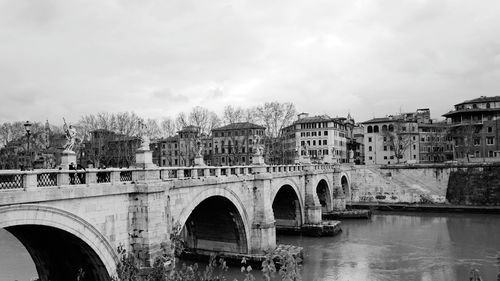 Arch bridge over river against buildings in city