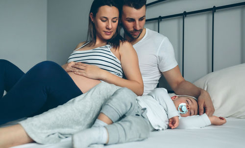 High angle view of pregnant woman with husband and son on bed at home