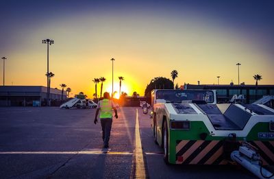 Rear view of people standing on road at sunset