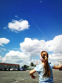 Rear view of girl standing on road against sky
