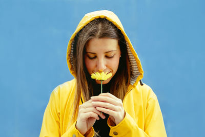 Woman smelling flowers against blue background