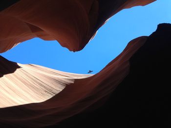 Low angle view of bird seen amidst rocky mountains on sunny day