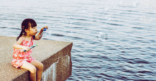 Girl blowing bubbles over sea