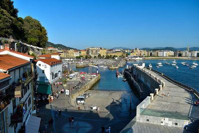 High angle view of harbor by buildings against clear blue sky