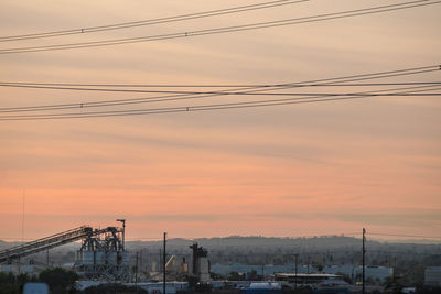 Power lines against sky during sunset